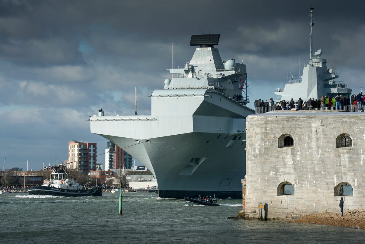this-is-hms-queen-elizabeth-making-its-first-voyage-as-an-official-member-of-the-royal-navy-tugboats-steered-her-past-the-round-tower-which-guards-the-mouth-of-portsmouth-harbour-at-56m-tall-the-carrier-dwarfed-it.jpg